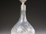 a clear glass perfume bottle with a silver top and a silver base