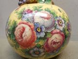 un vase avec des fleurs peintes dessus, posé sur une table