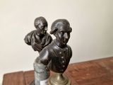 a close up of a statue of two men sitting on top of a wooden table