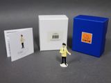 une petite figurine représentant un homme debout à côté d'une cabine téléphonique bleue