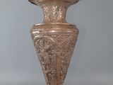 a person holding a bronze vase in their hand