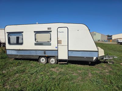 une photo d'une petite caravane garée dans un champ