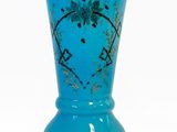 vase en verre bleu orné d'un motif floral sur fond blanc