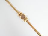 an image of a gold watch on a white surface with a white background