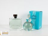 the bottle of cologne is next to the box on the table