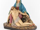a statue of jesus on the cross with a woman laying on the ground
