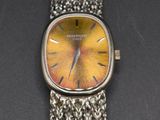 an image of a wrist watch with a yellow face on a black surface