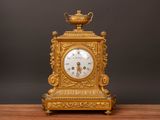 a gold clock sitting on top of a wooden table