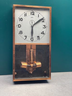 une horloge posée sur une table devant un mur vert