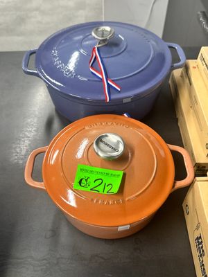 Plusieurs casseroles et poêles sont posées sur une table dans un magasin.