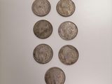 a group of six different types of coins on display in a glass case