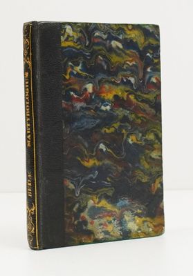 un vieux livre à la couverture noire posé sur une table blanche