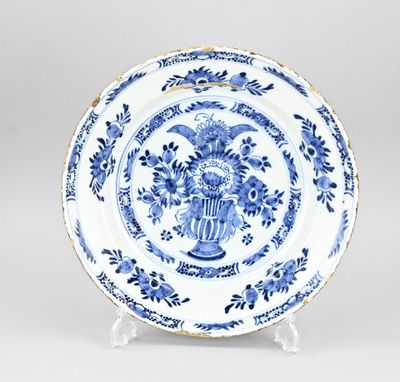 une assiette bleue et blanche sur laquelle est représenté un vase de fleurs