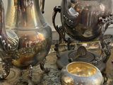 a lot of silver teapots and cups on a table