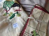 several pieces of cloth with embroidered designs on them sitting on a bed