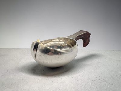 une théière en argent avec une poignée en bois posée sur une table