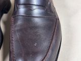 someone is wearing a pair of brown shoes on a white surface