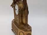 a gold clock sitting on top of a wooden table