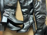 deux paires de bottes noires ornées de boucles, posées sur un carton