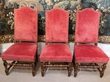 pair of red velvet upholstered chairs in front of a tapestry