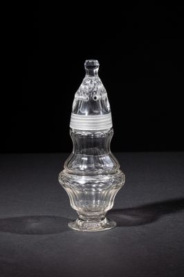 an old glass bottle with a lid on a black surface