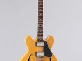 une guitare électrique jaune accrochée à un mur sur fond blanc