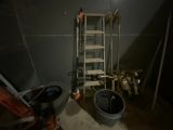 une pièce faiblement éclairée, avec une échelle, des seaux et des toilettes à l'intérieur