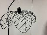 une lampe en métal noir posée sur un pied, à côté d'une boîte blanche