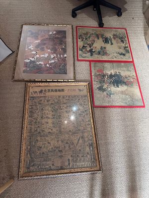 trois tableaux encadrés posés par terre dans un salon