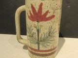 a coffee mug with a red flower on it on a table