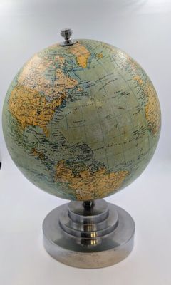 un petit globe posé sur un socle, sur une surface blanche