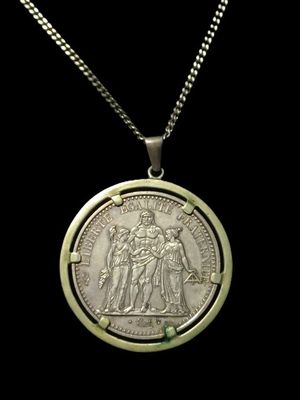 a close up of a coin on a chain on a black background