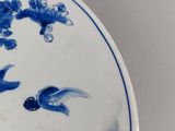 a blue and white plate with birds and flowers on it