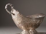 a silver gravy on a silver plate on a table
