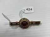 a close up of a gold and red broochle on a white surface