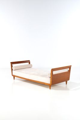 une photo d'un lit avec un cadre en bois et des draps blancs