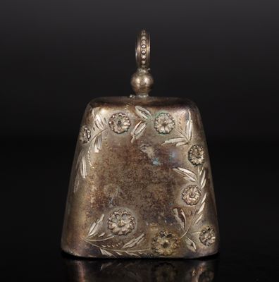 une vieille clochette en argent ornée d'un motif floral