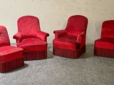 three red chairs and a ottoman in a room with a wall in the background