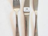 trois fourchettes et un couteau sur une table blanche