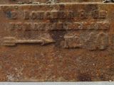 a rusted sign on the side of a building