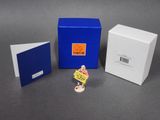 une petite figurine représentant une femme tenant une pancarte devant une boîte bleue