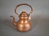 a small copper tea kettle on a gray surface