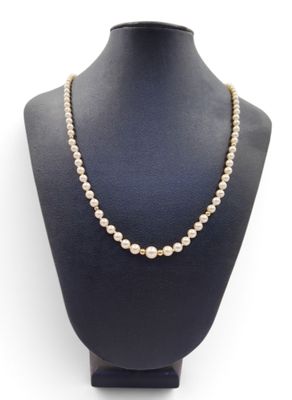 a white pearl necklace on a mannequin with a gold clasp