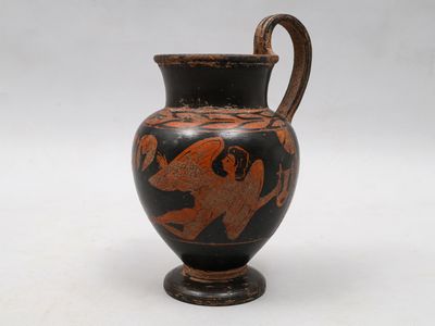 un vase noir et rouge posé sur une surface blanche