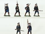 several figurines of men in uniforms with weapons on a white surface