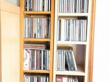 une grande bibliothèque en bois remplie de DVD et de CD