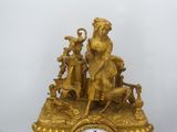 a gold clock with a man and a woman on it