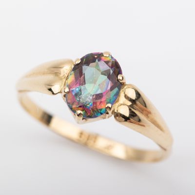 un gros plan d'une bague en or sertie d'une pierre aux couleurs de l'arc-en-ciel