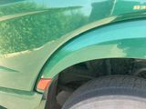 a close up of a green truck ' s fender and wheel