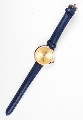 gros plan d'une montre sur une surface blanche avec un bracelet bleu